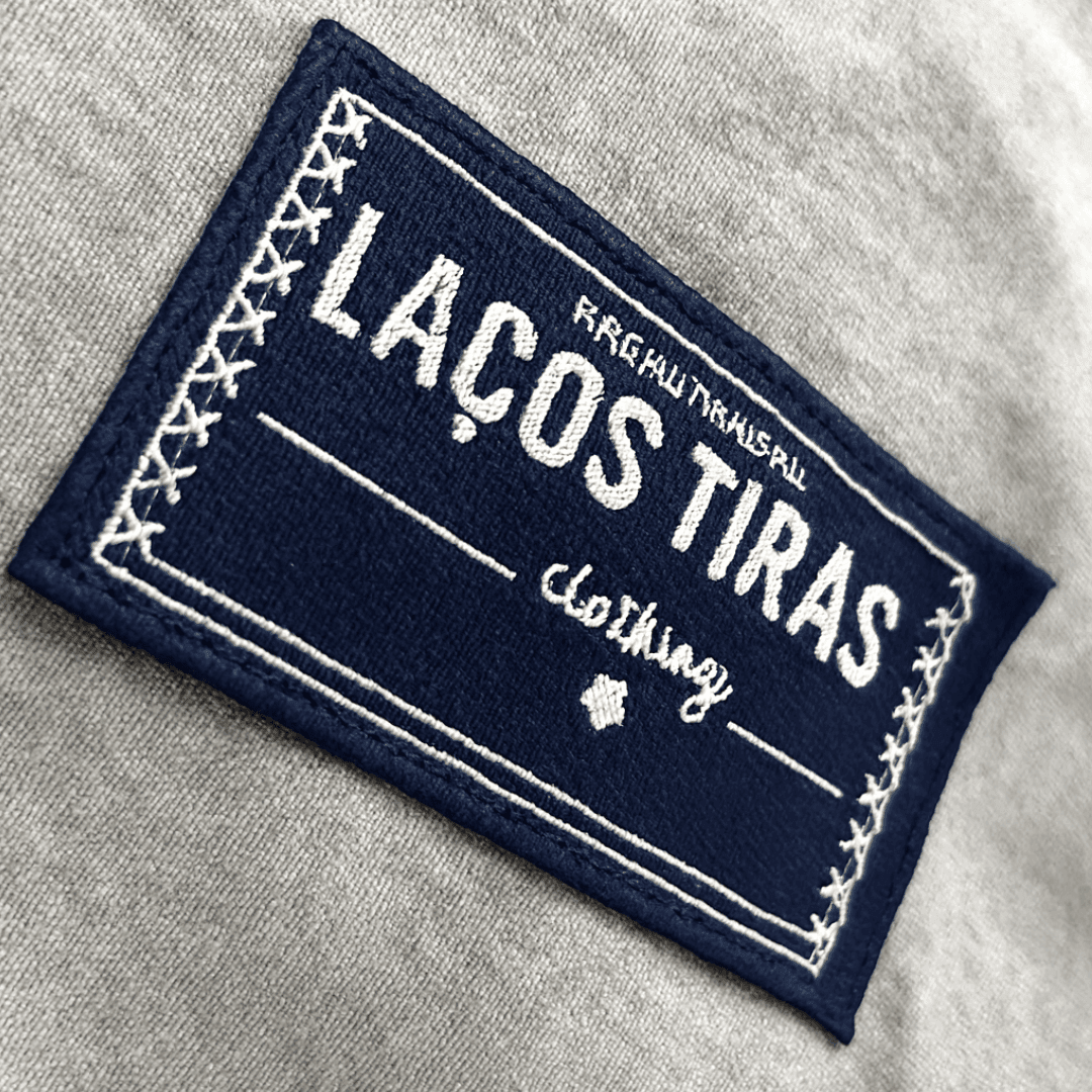 Close-up of a navy clothing label with white stitching and text on gray fabric.